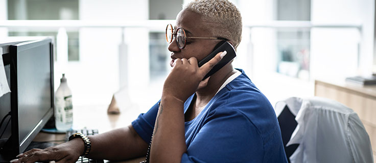 medical administrative assistant on phone at desk.