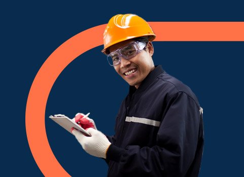 Man in orange hard hat and safety goggles making notes on clipboard.