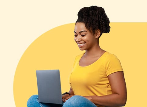 woman in a yellow t-shirt working on a laptop.