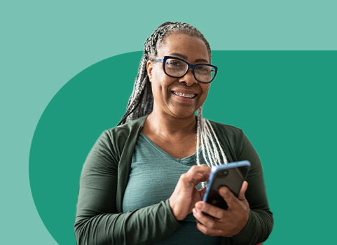 woman with glasses wearing green using cellphone on green background.