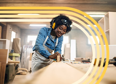 Woman in denim shirt and apron doing woodwork.