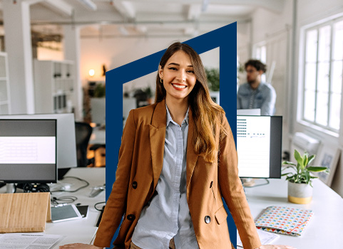 Smiling woman in office wearing brown coat.