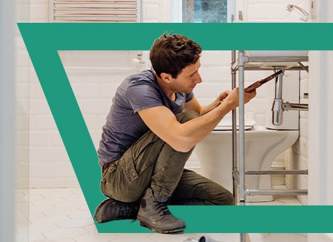 Man working on pipes on bathroom sink.