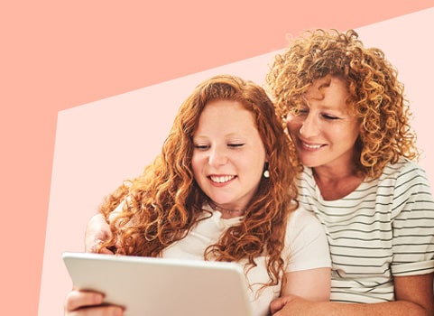 two women smiling and working on laptop.