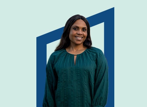 Woman in dark green blouse in front of blue background.