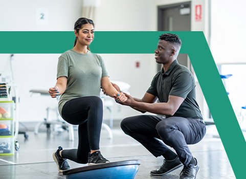 Physical therapist helping woman balance in therapy gym.