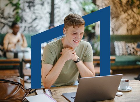 Man in tshirt studying with laptop at a cafe.