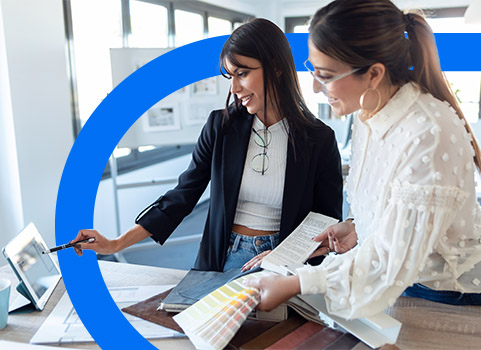 Two women reviewing designs on tablet.