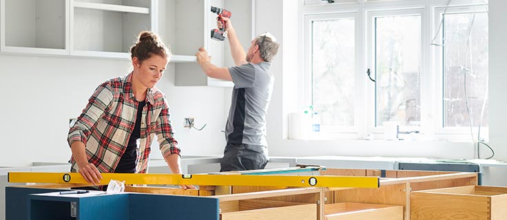 two people remodeling a home kitchen.